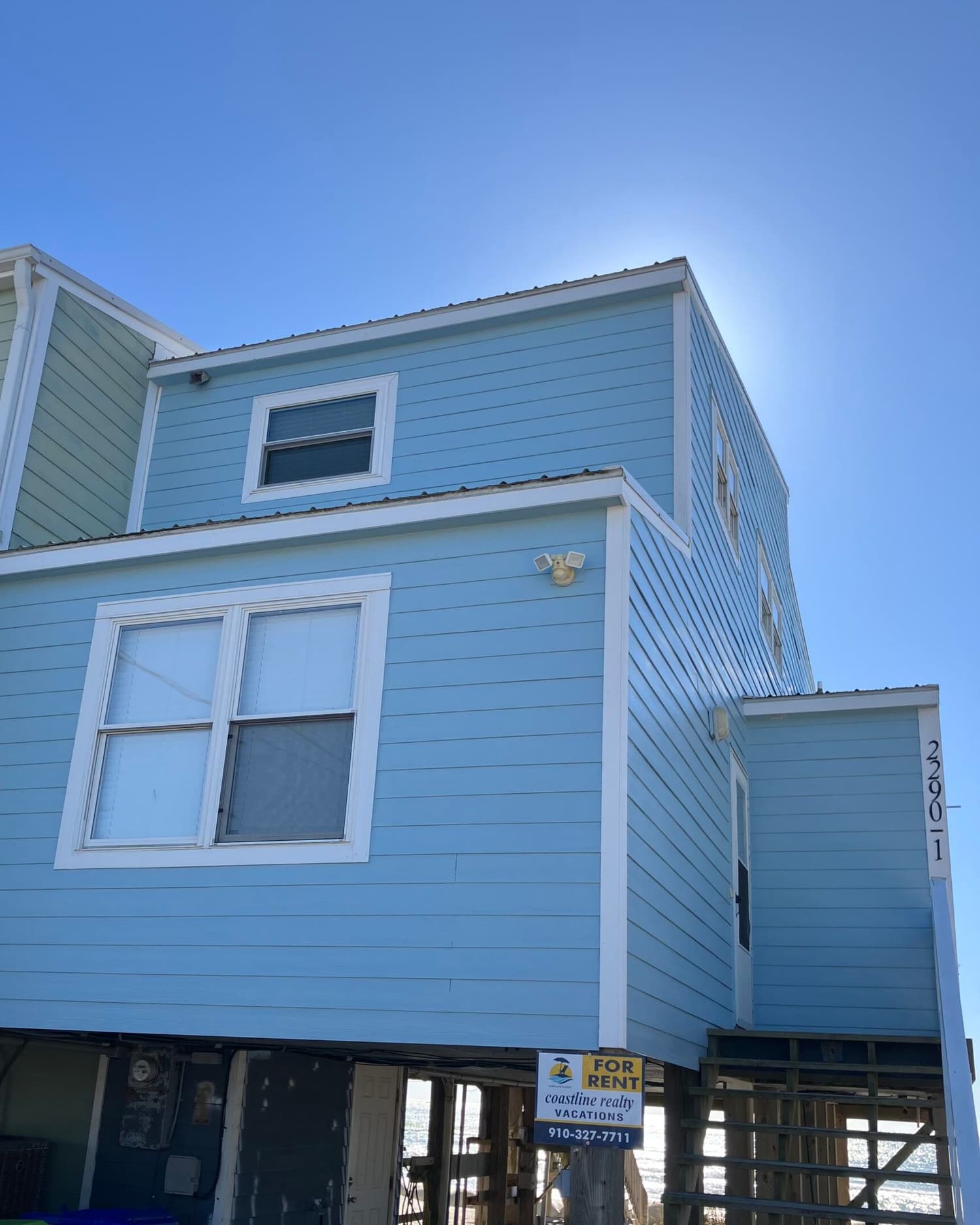 A coastal home on pilings after a full exterior repaint by S&S, with their sign in the yard