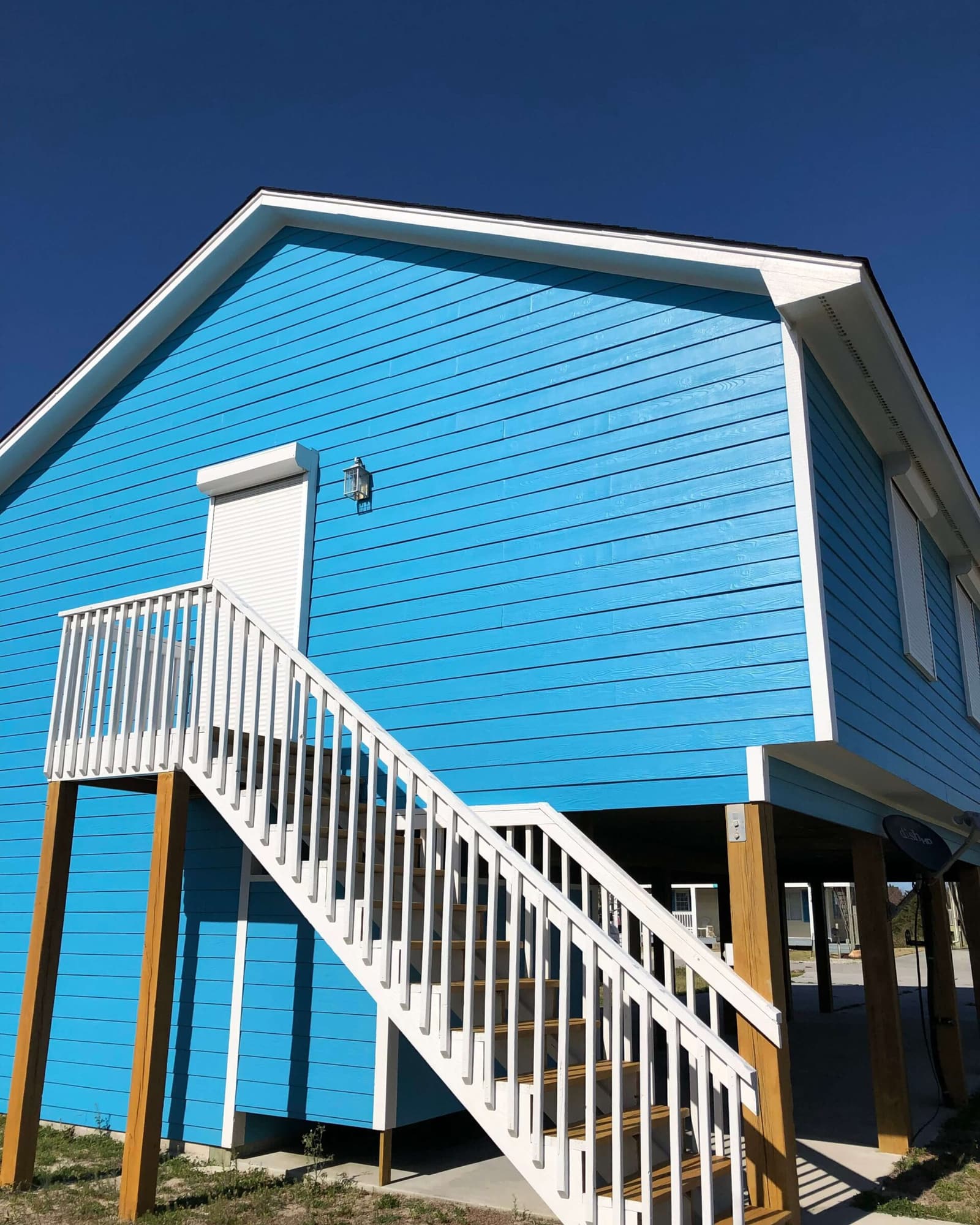 A Topsail-coast beach house on pilings, freshly repainted a deep coastal blue by S&S Painting & Pressure Washing near Sneads Ferry, NC